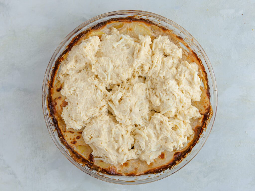 Assemble & Bake 🍽Cheesy Potato Cobbler – The Ultimate Comfort Food! -A golden-brown cheesy potato cobbler in a baking dish, with gooey melted cheese on top.