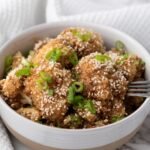 Crispy teriyaki-glazed cauliflower wings served on a plate with sesame seeds and green onions.