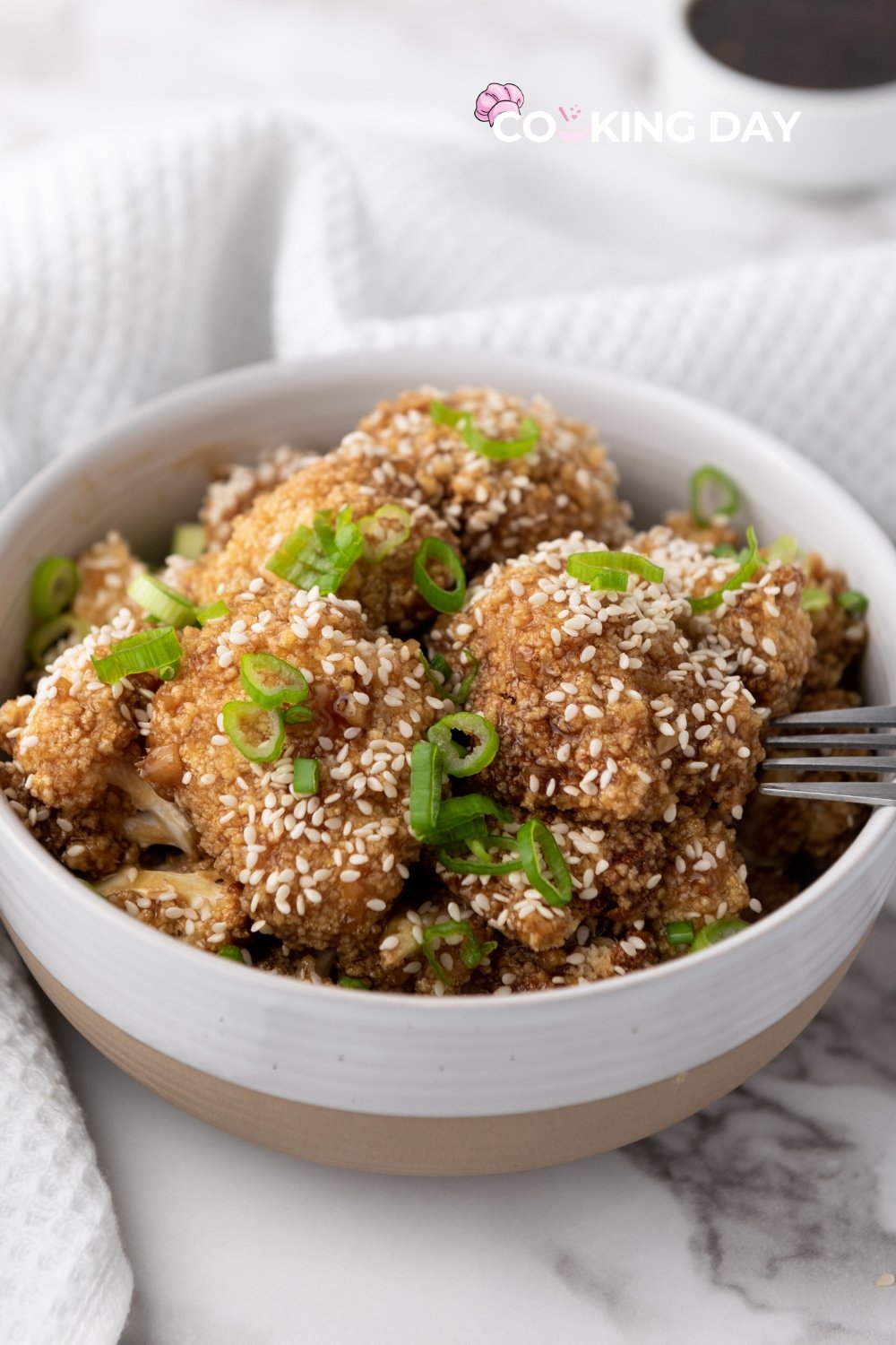 Crispy teriyaki-glazed cauliflower wings served on a plate with sesame seeds and green onions.