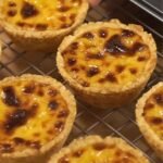 A tray of freshly baked egg tarts with golden edges and smooth, jiggly centers.