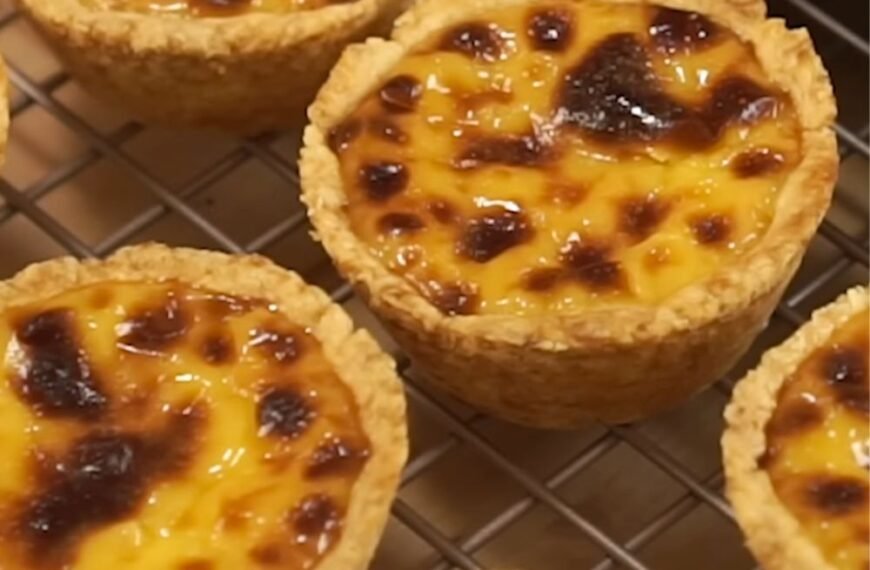A tray of freshly baked egg tarts with golden edges and smooth, jiggly centers.