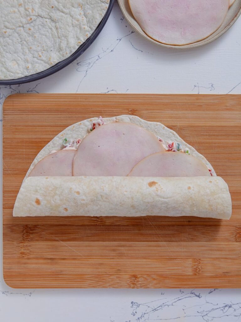 Roll tightly -Spread the filling - Ingredients- Easy Turkey Tomato Pinwheels – Creamy No Cook Appetizer