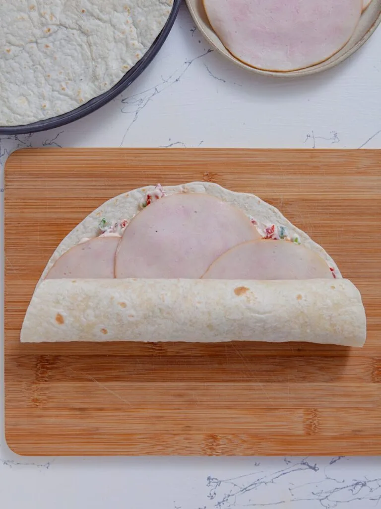 Roll tightly -Spread the filling - Ingredients- Easy Turkey Tomato Pinwheels – Creamy No Cook Appetizer