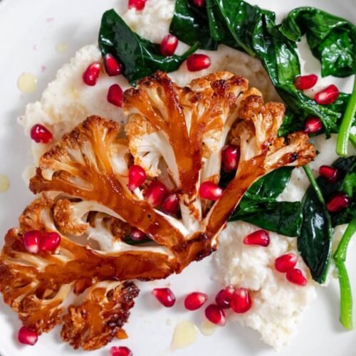 Roasted Honey Sriracha Cauliflower Steak served over creamy mashed cauliflower with spinach and pomegranate seeds